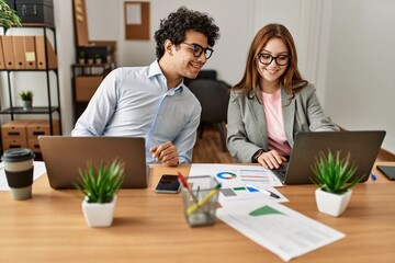 Obraz premium Two business workers smiling happy working using laptop at the office.