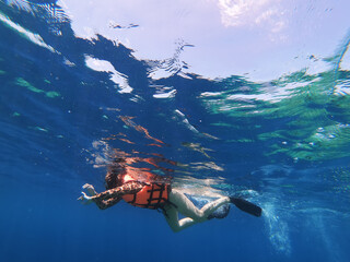 Fototapeta na wymiar Silhouette of scuba diver and sunlight in the blue water