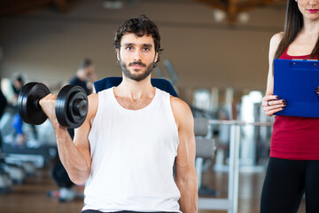 Fototapeta na wymiar Man working out in a gym with his personal trainer