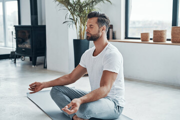 Concentrated young man doing yoga - Powered by Adobe