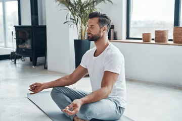  Geconcentreerde jonge man die yoga doet © gstockstudio