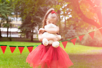 Watermelon party, picnic for children in park. watermelon day. Cute small girl with hat and with toy bear with watermelon hat
