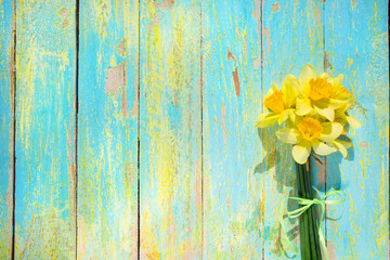 bouquet of yellow daffodils on a textured wooden multicolored background