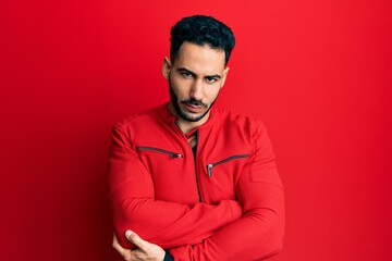 Fototapeta premium Young hispanic man wearing red leather jacket skeptic and nervous, disapproving expression on face with crossed arms. negative person.