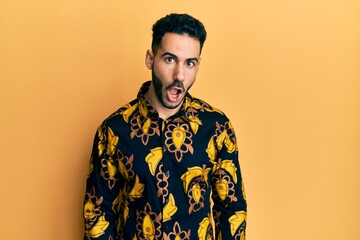 Young hispanic man wearing casual shirt afraid and shocked with surprise expression, fear and excited face.