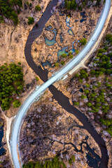 winding road next to river among forests and swamps, the nature of the Urals, the view from the drone.