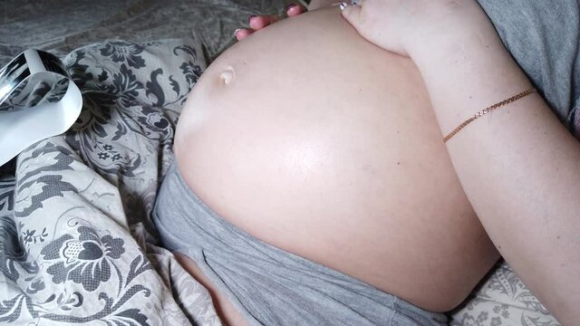 Beautiful pregnant woman feeling kick of baby. Mother-to-be watching sonogram picture