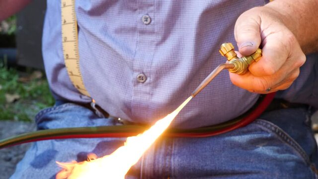 Maintenance worker using an acetylene torch to weld a pipe