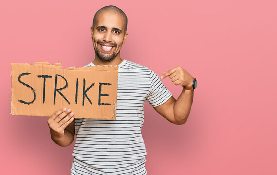 Hispanic adult man holding strike banner cardboard pointing finger to one self smiling happy and proud