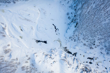 Flying above frozen forest and winding river in winter