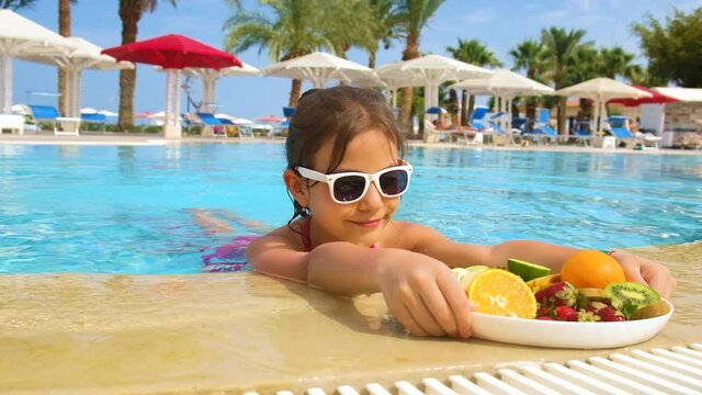 Child girl eats fruit in the pool. Selective focus.