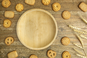 Empty wooden plate, wheat cookies, wheat ears on wooden background. Harvest, Shavuot concept. 