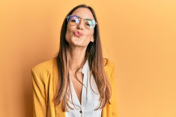 Young beautiful woman wearing business style and glasses looking at the camera blowing a kiss on air being lovely and sexy. love expression.