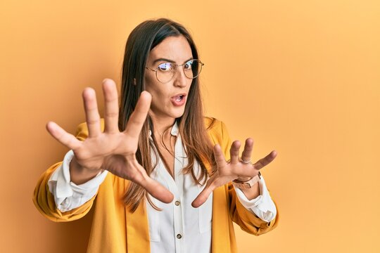 Young beautiful woman wearing business style and glasses doing stop gesture with hands palms, angry and frustration expression