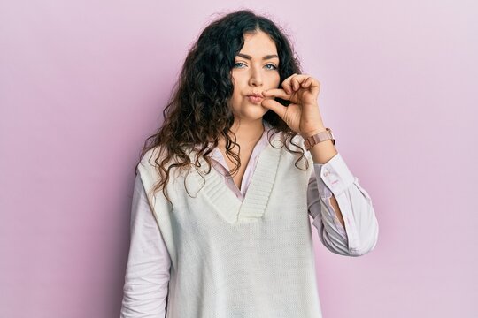 Young brunette woman with curly hair wearing casual clothes mouth and lips shut as zip with fingers. secret and silent, taboo talking