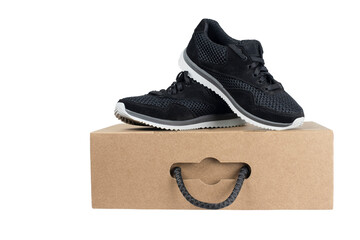On a cardboard box for footwear there are dark sneakers from fabric with a strong sole for sports exercises. Sneakers for boys and girls on a cardboard box