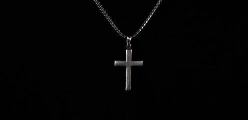 Praying with a rosary. hand of Catholic man with rosary on black background. Hands holding a silver rosary or cross pendant of Jesus Christ. Crucifix and hand on black background. Praying God concept