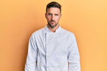 Handsome man with beard wearing professional cook uniform skeptic and nervous, frowning upset because of problem. negative person.