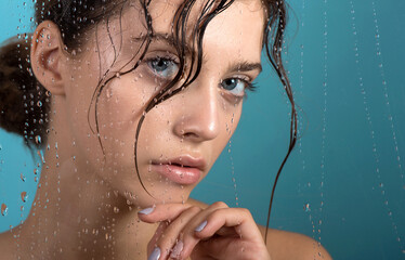 Beautiful young woman with clean perfect skin and water moisture drops touching face.