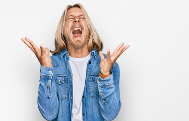 Caucasian man with blond long hair wearing casual denim jacket celebrating mad and crazy for...