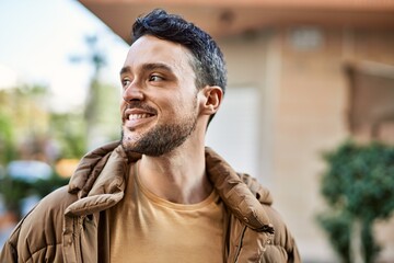 Young hispanic man smiling happy standing at the city.