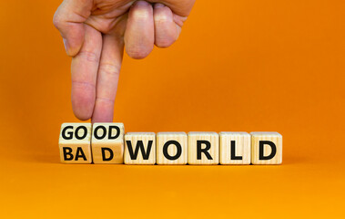 Good or bad world symbol. Businessman turns wooden cubes and changes words 'bad world' to 'good world'. Beautiful orange table, orange background, copy space. Business and good or bad world concept.
