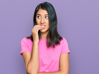 Beautiful asian young woman wearing casual pink t shirt looking stressed and nervous with hands on mouth biting nails. anxiety problem.