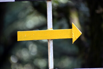 Yellow metal arrow at park. Selective Focus On Subject, Background Blur