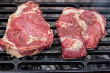 Pork steaks have just been placed on a cast iron wire rack
