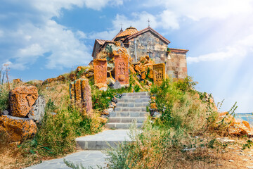 Scenic view of the old Hayravank Monastery on the shores of Lake Sevan on a sunny day, blue sky and fluffy clouds. Armenia