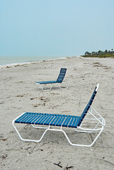 Fototapeta na wymiar Two empty sun loungers at empty beach