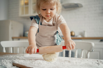 A cheerful girl of European appearance, a blonde child. The children's mood is good. Prepare dough...