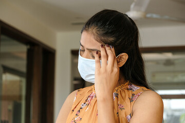 Closeup shot of an Asian girl having headache pain and wearing a mask - new normal concept