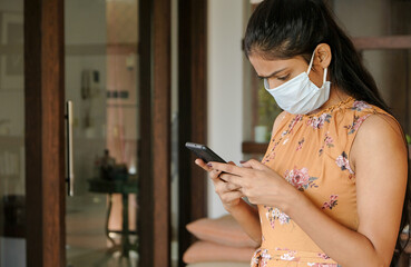 Closeup shot of an Asian girl wearing a mask and looking at her phone - new normal concept
