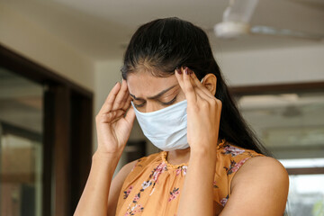 Closeup shot of an Asian girl having headache pain and wearing a mask - new normal concept