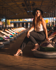 Lifestyle, Caucasian brunette with.long pants, white t-shirt and black hat in an amusement park in the bumper cars