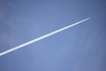 Jetstream follows white plane three quarters of the way across a blue mottled sky