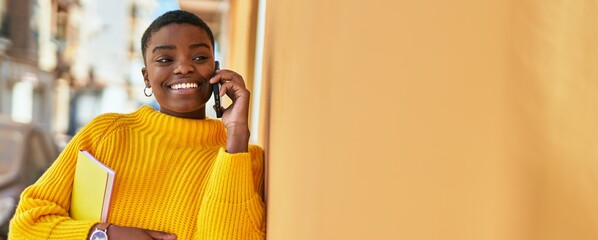 Young african american woman smiling happy talking on the smartphone at the city