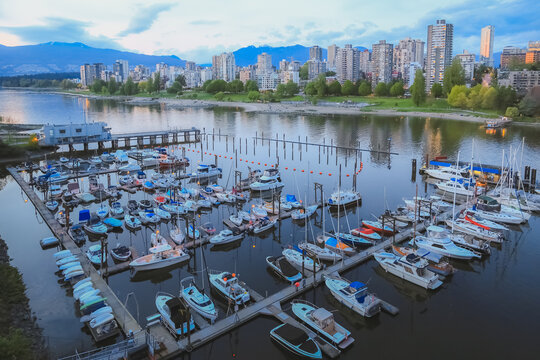 Summer evening view over boats of Burrard Civic Marina and Sunset Beach across the inlet in English Bay with cityscape skyline of downtown Vancouver, British Columbia, Canada.