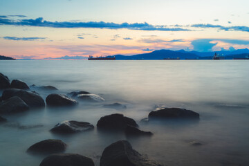 Sunset or sunrise seascape from rocky shore at Kitsilano Beach on an idyllic summer evening in Vancouver, B.C., Canada.