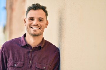 Young hispanic man smiling happy standing at the city.