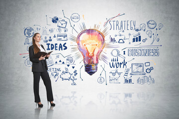 Businesswoman with notebook in hands, light bulb on grey wall © ImageFlow