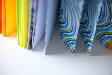 fanciful book with multicoloured card-stock and plain wavy pattern paper - fan composition or various segments of colour - photographed with a macro lens - shallow depth of field