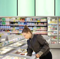 Woman choosing frozen food from a supermarket freezer