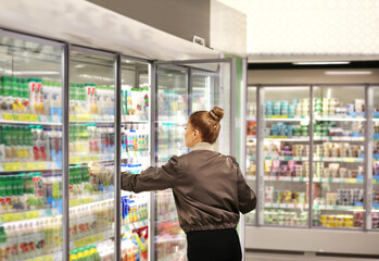 Woman choosing frozen food from a supermarket freezer