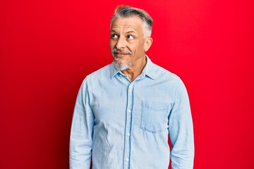 Middle age grey-haired man wearing casual clothes smiling looking to the side and staring away thinking.