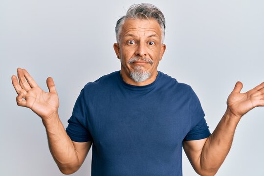 Middle age grey-haired man wearing casual clothes clueless and confused with open arms, no idea and doubtful face.