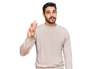 Young hispanic man wearing casual clothes showing and pointing up with fingers number three while smiling confident and happy.