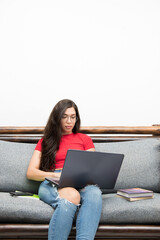 Colombian girl writes on her laptop sitting on the sofa at home