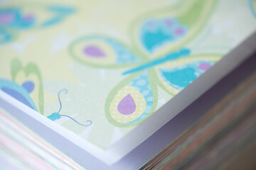 stack of fancy scrapbooking paper (with colourful butterflies) photographed using a macro lens, featuring a shallow depth of field